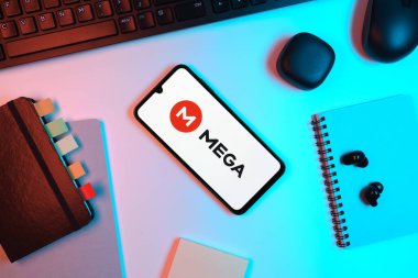 Prag, Çek Cumhuriyeti - 05: 18 2025: Mega logosunu gösteren bir telefonla ofis masasına yerleştirilmiş nesneler.