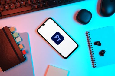 Prag, Çek Cumhuriyeti - 05: 18 2025: Premiere Pro logosunu gösteren bir telefonla ofis masasına yerleştirilmiş nesneler.