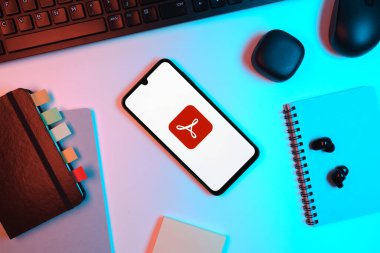 Prag, Çek Cumhuriyeti - 05: 18 2025: Akrobat Okuyucu logosunu gösteren bir telefonla ofis masasına yerleştirilmiş nesneler.