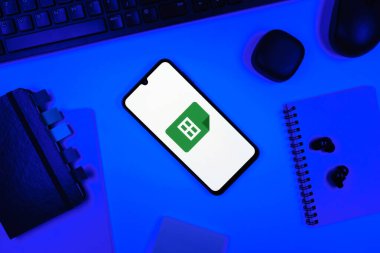 Prag, Çek Cumhuriyeti - 05: 18 2025: Google Sheets logosunu gösteren bir telefonla ofis masasına yerleştirilmiş nesneler.