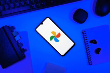 Prag, Çek Cumhuriyeti - 05: 18 2025: Google Photos logosunu gösteren bir telefonla ofis masasına yerleştirilmiş nesneler.