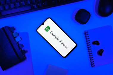 Prag, Çek Cumhuriyeti - 05: 18 2025: Google Sheets logosunu gösteren bir telefonla ofis masasına yerleştirilmiş nesneler.