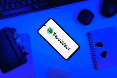 Prag, Çek Cumhuriyeti - 05: 18 2025: TripDanışman logosunu gösteren bir telefonla ofis masasına yerleştirilmiş nesneler.