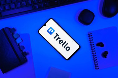 Prag, Çek Cumhuriyeti - 05: 18 2025: Trello logosunu gösteren bir telefonla ofis masasına yerleştirilmiş nesneler.