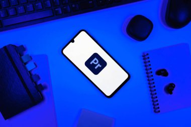 Prag, Çek Cumhuriyeti - 05: 18 2025: Premiere Pro logosunu gösteren bir telefonla ofis masasına yerleştirilmiş nesneler.