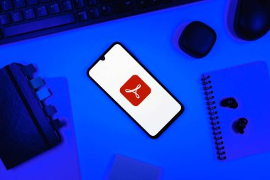 Prag, Çek Cumhuriyeti - 05: 18 2025: Akrobat Okuyucu logosunu gösteren bir telefonla ofis masasına yerleştirilmiş nesneler.