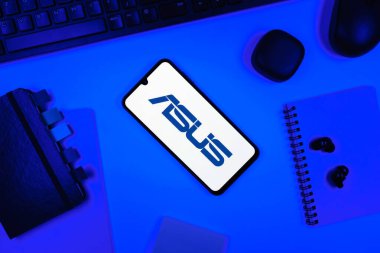 Prag, Çek Cumhuriyeti - 05: 18 2025: Asus logosunu gösteren bir telefonla ofis masasına yerleştirilmiş nesneler.