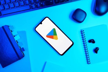Prag, Çek Cumhuriyeti - 05: 18 2025: Google Play logosunu gösteren bir telefonla ofis masasına yerleştirilmiş nesneler.