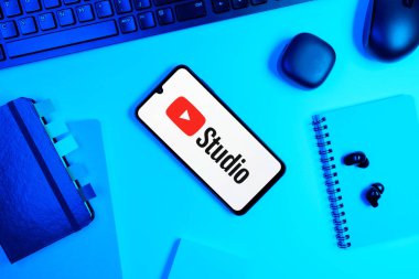 Prag, Çek Cumhuriyeti - 05: 18 2025: Youtube Stüdyo logosunu gösteren bir telefonla ofis masasına yerleştirilmiş nesneler.