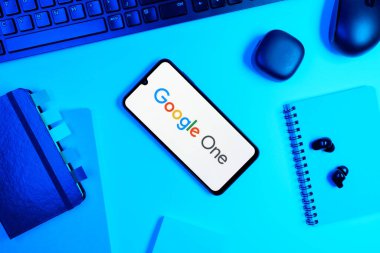 Prag, Çek Cumhuriyeti - 05: 18 2025: Google One logosunu gösteren bir telefonla ofis masasına yerleştirilmiş nesneler.