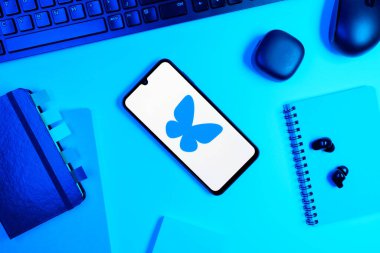 Prag, Çek Cumhuriyeti - 05: 18 2025: Bluesky logosunu gösteren bir telefonla ofis masasına yerleştirilmiş nesneler.