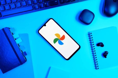 Prag, Çek Cumhuriyeti - 05: 18 2025: Google Photos logosunu gösteren bir telefonla ofis masasına yerleştirilmiş nesneler.