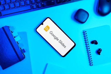 Prag, Çek Cumhuriyeti - 05: 18 2025: Google Slides logosunu gösteren bir telefonla ofis masasına yerleştirilmiş nesneler.