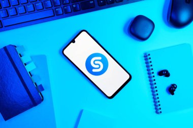 Prag, Çek Cumhuriyeti - 05: 18 2025: Shazam logosunu gösteren bir telefonla ofis masasına yerleştirilmiş nesneler.