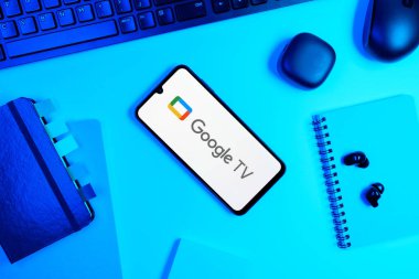 Prag, Çek Cumhuriyeti - 05: 18 2025: Google TV logosunu gösteren bir telefonla ofis masasına yerleştirilmiş nesneler.
