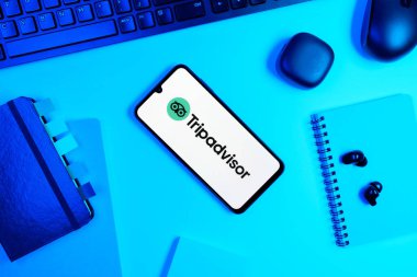 Prag, Çek Cumhuriyeti - 05: 18 2025: TripDanışman logosunu gösteren bir telefonla ofis masasına yerleştirilmiş nesneler.