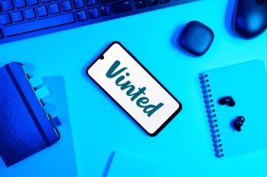 Prag, Çek Cumhuriyeti - 05: 18 2025: Vinted logosunu gösteren bir telefonla ofis masasına yerleştirilmiş nesneler.