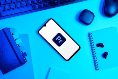 Prag, Çek Cumhuriyeti - 05: 18 2025: Premiere Pro logosunu gösteren bir telefonla ofis masasına yerleştirilmiş nesneler.