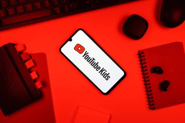 Prag, Çek Cumhuriyeti - 05: 18 2025: Youtube Çocuk logosunu gösteren bir telefonla ofis masasına yerleştirilmiş nesneler.