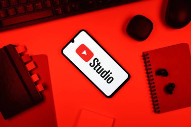 Prag, Çek Cumhuriyeti - 05: 18 2025: Youtube Stüdyo logosunu gösteren bir telefonla ofis masasına yerleştirilmiş nesneler.