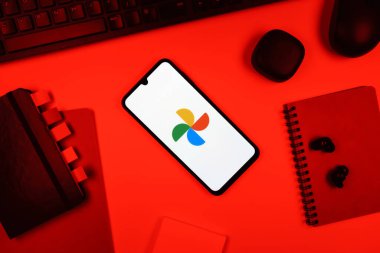 Prag, Çek Cumhuriyeti - 05: 18 2025: Google Photos logosunu gösteren bir telefonla ofis masasına yerleştirilmiş nesneler.