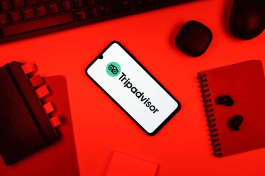 Prag, Çek Cumhuriyeti - 05: 18 2025: TripDanışman logosunu gösteren bir telefonla ofis masasına yerleştirilmiş nesneler.