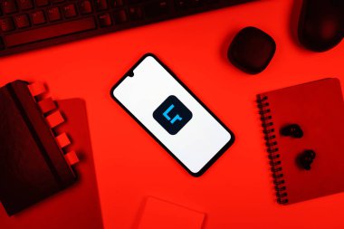 Prag, Çek Cumhuriyeti - 05: 18 2025: Bir ofis masasına yerleştirilmiş nesneler Lightroom logosunu gösteren bir telefonla.