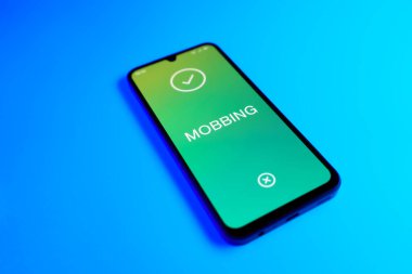 Açık mavi arkaplandaki telefon Mobbing metnini görüntüler.