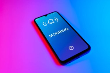 Mor ve mavi arkaplandaki telefon Mobbing metnini görüntüler.
