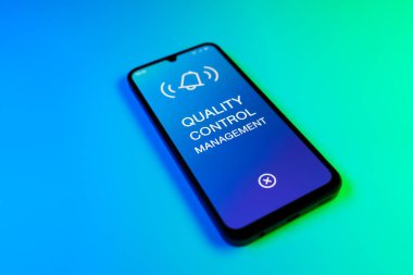Mavi ve yeşil arkaplandaki telefon Kalite Kontrol Yönetimi metnini görüntüler.