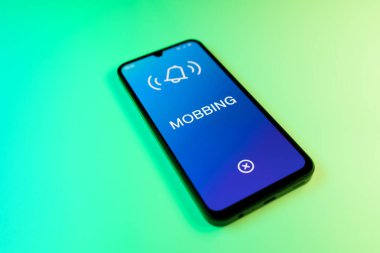 Yeşil arkaplandaki telefon Mobbing metnini görüntüler.