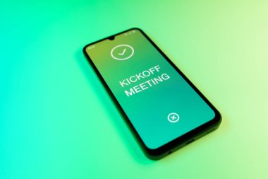 Yeşil arkaplan üzerindeki telefon Kickoff toplantı metnini görüntüler.