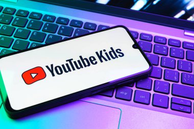 Prag, Çek Cumhuriyeti - 08 01 2025: Laptop klavyesinde duran bir cep telefonu Youtube Kids logosunu gösteriyor. Youtube Kids çocuk dostu video içeriği için bir platformdur.