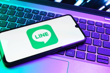 Prag, Çek Cumhuriyeti - 08 01 2025: Dizüstü bilgisayarın üzerinde duran bir cep telefonu Hat logosunu gösterir. Line aramalar, mesajlar ve çokluortam paylaşımı için bir mesajlaşma uygulamasıdır.