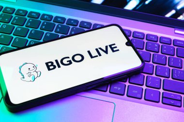 Prag, Çek Cumhuriyeti - 08 01 2025: Dizüstü bilgisayarın üzerinde duran bir cep telefonu Bigo Live logosunu gösteriyor. Bigo Live canlı yayın ve sosyal etkileşim için bir platformdur.