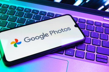 Prag, Çek Cumhuriyeti - 08 01 2025: Laptop klavyesinde duran bir cep telefonu Google Photos logosunu görüntüler. Google Fotoğrafları fotoğraf ve videoları saklamak ve düzenlemek için bir platformdur.