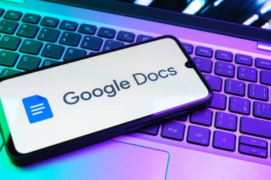 Prag, Çek Cumhuriyeti - 08 01 2025: Dizüstü bilgisayarda bulunan bir cep telefonu Google Docs logosunu görüntüler. Google Docs metin belgeleri oluşturmak ve düzenlemek için bir platformdur.