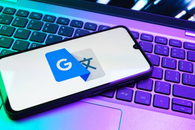 Prag, Çek Cumhuriyeti - 08 01 2025: Dizüstü bilgisayarda bulunan bir cep telefonu Google Translate logosunu görüntüler. Google Çevirisi metni ve konuşmayı diller arası çevirmek için bir platformdur..