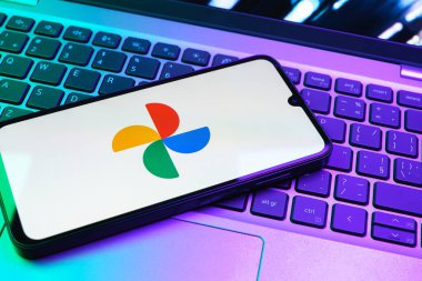 Prag, Çek Cumhuriyeti - 08 01 2025: Laptop klavyesinde duran bir cep telefonu Google Photos logosunu görüntüler. Google Fotoğrafları fotoğraf ve videoları saklamak ve düzenlemek için bir platformdur.