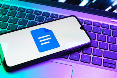 Prag, Çek Cumhuriyeti - 08 01 2025: Dizüstü bilgisayarda bulunan bir cep telefonu Google Docs logosunu görüntüler. Google Docs metin belgeleri oluşturmak ve düzenlemek için bir platformdur.