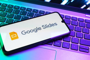 Prag, Çek Cumhuriyeti - 08 01 2025: Laptop klavyesinde duran bir cep telefonu Google Slides logosunu görüntüler. Google Slides sunumlar ve slayt gösterileri oluşturmak için bir platformdur.