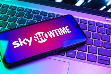 Prag, Çek Cumhuriyeti - 08 01 2025: Dizüstü bilgisayarın üzerinde duran bir cep telefonu SkyShowtime logosunu gösteriyor. SkyShowtime, sinema ve televizyon dizileri için bir yayın platformudur..
