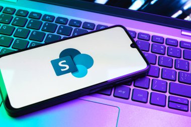 Prag, Çek Cumhuriyeti - 08 01 2025: Dizüstü bilgisayarın üzerinde duran bir cep telefonu Microsoft Sharepoint logosunu gösteriyor. Microsoft Sharepoint işbirliği ve belge yönetimi için bir platformdur.