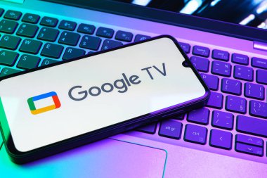 Prag, Çek Cumhuriyeti - 08 01 2025: Laptop klavyesinde uzanan bir cep telefonu Google TV logosunu gösteriyor. Google TV film, program ve uygulamalar için bir platformdur..