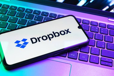 Prag, Çek Cumhuriyeti - 08 01 2025: Laptop klavyesinde duran bir cep telefonu Dropbox logosunu gösterir. Dropbox bulut depolama ve dosya paylaşımı için bir platformdur.