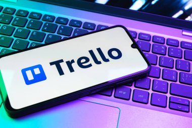 Prag, Çek Cumhuriyeti - 08 01 2025: Dizüstü bilgisayarın üzerinde duran bir cep telefonu Trello logosunu gösterir. Trello, tahta ve görevleri kullanarak proje yönetimi için bir platformdur.