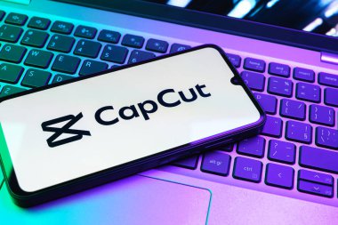 Prag, Çek Cumhuriyeti - 08 01 2025: Laptop klavyesinde duran bir cep telefonu CapCut logosunu gösteriyor. CapCut video düzenleme ve oluşturma için bir platformdur.