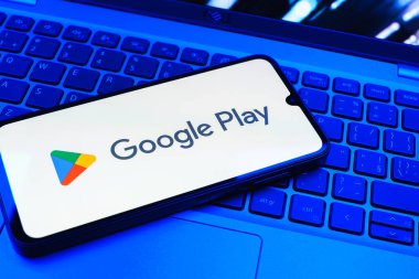 Prag, Çek Cumhuriyeti - 08 01 2025: Dizüstü bilgisayarda bulunan bir cep telefonu Google Play logosunu görüntüler. Google Play uygulamaları, oyunları ve dijital içeriği indirmek için bir platformdur.