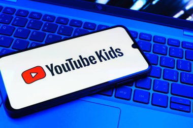 Prag, Çek Cumhuriyeti - 08 01 2025: Laptop klavyesinde duran bir cep telefonu Youtube Kids logosunu gösteriyor. Youtube Kids çocuk dostu video içeriği için bir platformdur.