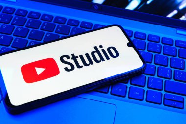 Prag, Çek Cumhuriyeti - 08 01 2025: Laptop klavyesinde duran bir cep telefonu Youtube Stüdyo logosunu görüntüler. Youtube Studio YouTube kanallarını yönetmek ve analiz etmek için bir platformdur.